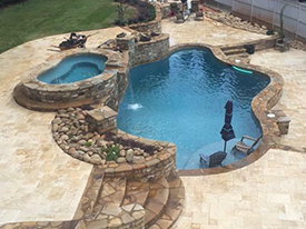 A backyard swimming pool with a hot tub and hardscapes.