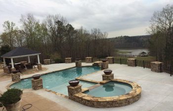 An outdoor swimming pool with a hot tub and water features installed by Premier Pool Enterprises