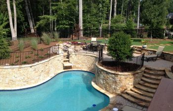 A backyard hardscaped patio with an outdoor swimming pool installed by Premier Pool Enterprises