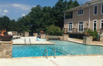 A residential house with an outdoor swimming pool with a hot tub and water features installed by Premier Pool Enterprises