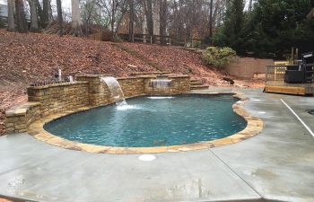 Backyard swimming pool with a hot tub and water features installed by Premier Pool Enterprises