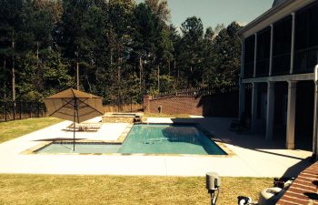 Backyard swimming pool with a hot tub and water features installed by Premier Pool Enterprises