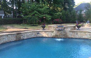 Backyard swimming pool with a hot tub and water features installed by Premier Pool Enterprises