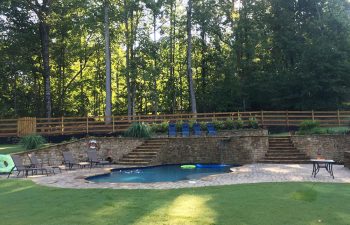 Backyard swimming pool with a hot tub and water features installed by Premier Pool Enterprises