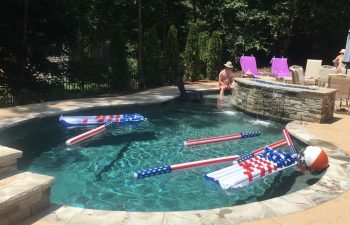 Swimming accessories floating on a ackyard swimming pool with a hot tub installed by Premier Pool Enterprises