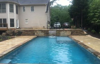 Backyard swimming pool with a waterfall installed by Premier Pool Enterprises