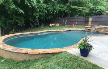 Backyard swimming pool with a hardscaped hot tub installed by Premier Pool Enterprises