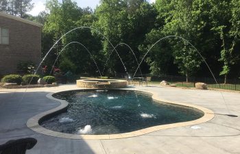 Backyard swimming pool with a hot tub and water features installed by Premier Pool Enterprises