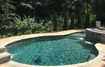 Backyard swimming pool with hot tub and waterfalls installed by Premier Pool Enterprises