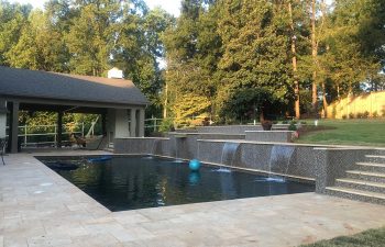 Backyard swimming pool with water features installed by Premier Pool Enterprises