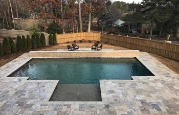 Backyard modern swimming pool stone deck installed by Premier Pool Enterprises