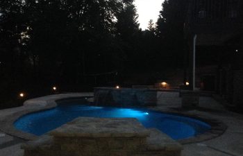 Backyard lit swimming pool in the evening.