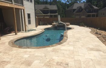 Backyard swimming pool with hot tub and water features installed by Premier Pool Enterprises