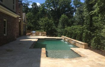 Backyard swimming pool with water features installed by Premier Pool Enterprises