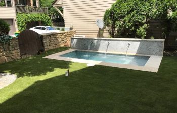 Backyard swimming pool with water features installed by Premier Pool Enterprises