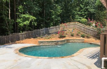 Backyard swimming pool with water features installed by Premier Pool Enterprises