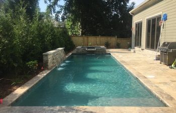 Backyard swimming pool with hot tub and water features installed by Premier Pool Enterprises