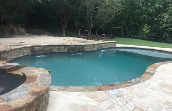 Backyard swimming pool with hot tub and water features installed by Premier Pool Enterprises