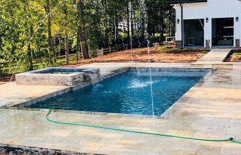 Backyard swimming pool with hot tub and water features installed by Premier Pool Enterprises