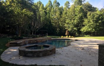 Backyard swimming pool with hot tub and water features installed by Premier Pool Enterprises