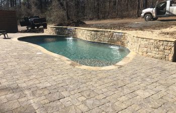 Backyard swimming pool with water features installed by Premier Pool Enterprises.