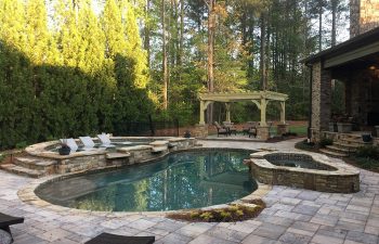 Home outdoor living space with hardscaped pool with spa zone.