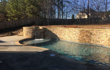 Backyard swimming pool with hot tub and waterfall designed and installed by Premier Pool Enterprises.
