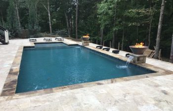 backyard stone patio with a modern swimming pool with water features