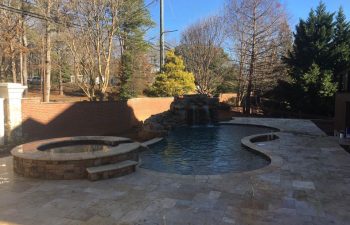 backyard swimming pool with hot tub and hardscaped waterfall