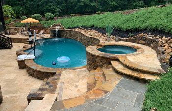 backyard swimming pool with hot tub and hardscaped waterfall