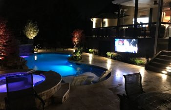 a lit backyard swimming pool at night