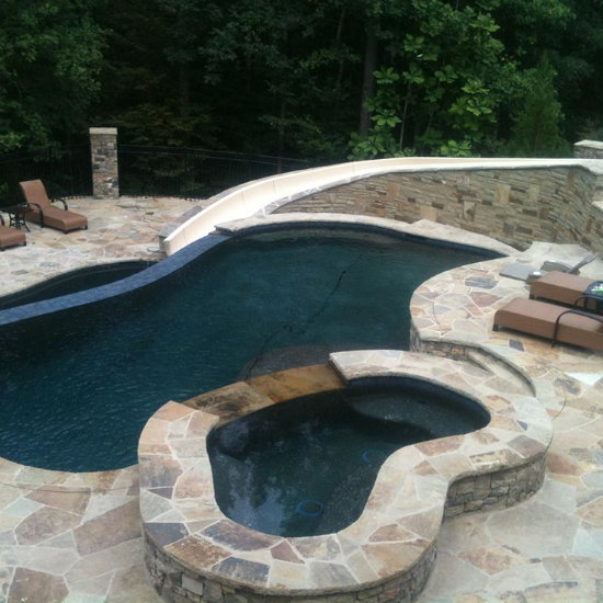 yard swimming pool with a hot tub and flagstone deck