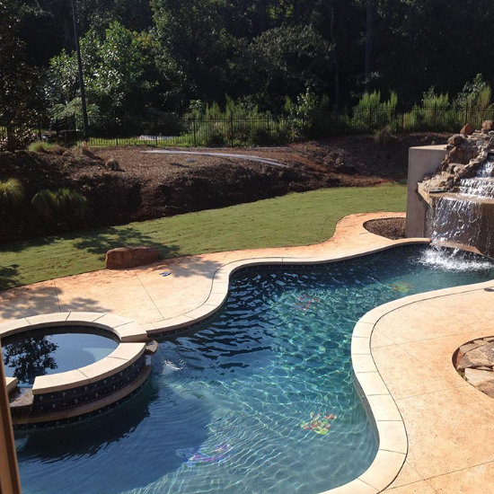 custom yard swimming pool with a hot tub and hardscaped waterfall