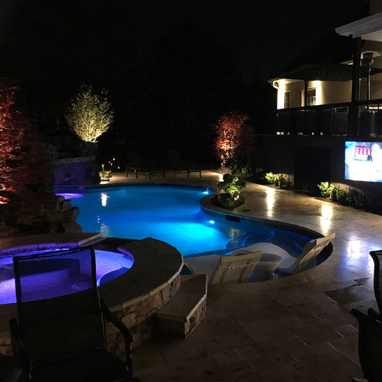 a lit backyard swimming pool at night