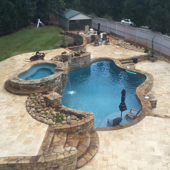 backyard swimming pool with hot tub and hardscaped waterfall