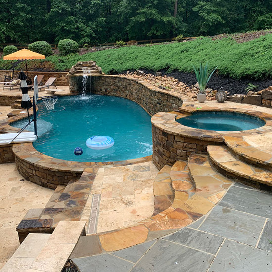 backyard swimming pool with hot tub and hardscaped waterfall