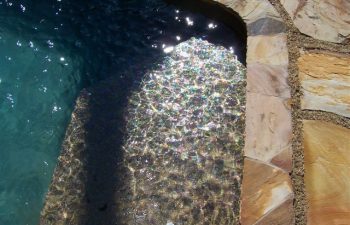 Edge of a swimming pool with a flagstone deck.