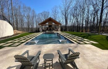 Pool chairs on a deck of a modern backyard pool with water features