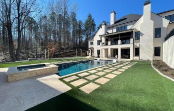 A residential house with an outdoor swimming pool with a hot tub and water features installed by Premier Pool Enterprises