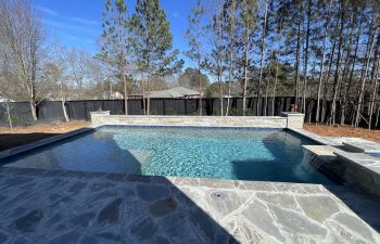 Backyard swimming pool with a waterfalls installed by Premier Pool Enterprises