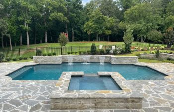 Backyard swimming pool with a waterfalls installed by Premier Pool Enterprises